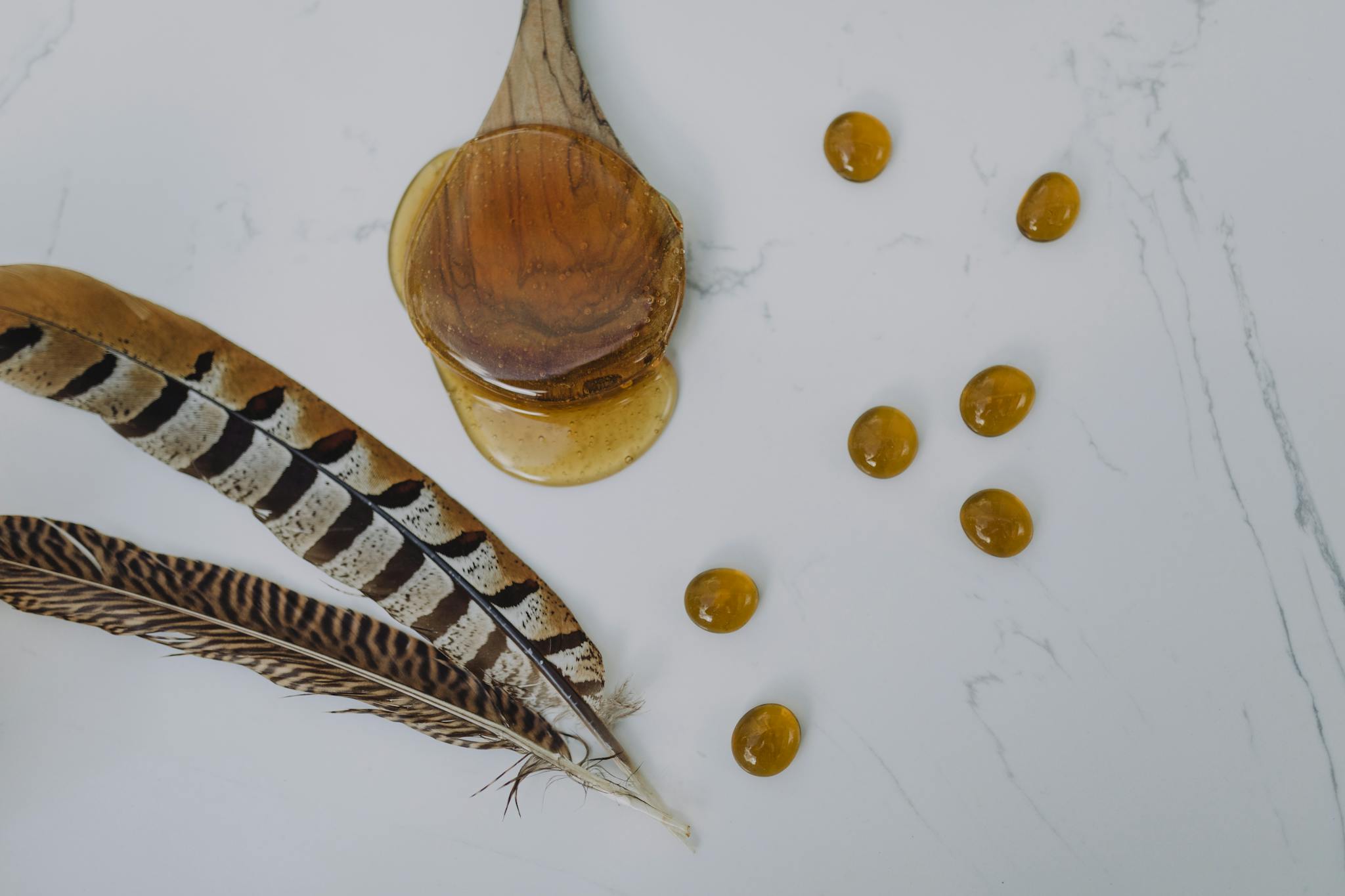 A serene arrangement of honey, feathers, and amber beads creating a calming spa-like atmosphere.