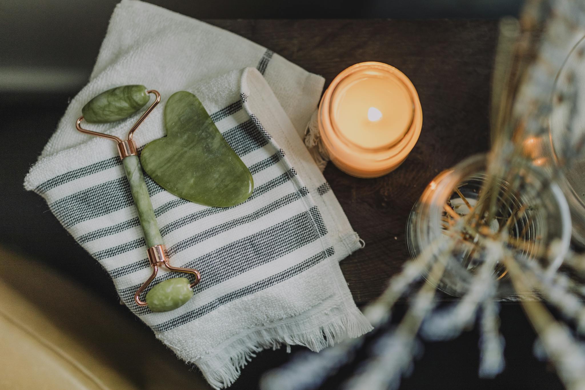 A serene spa setup featuring a jade roller, gua sha, towel, and candle for ultimate relaxation.