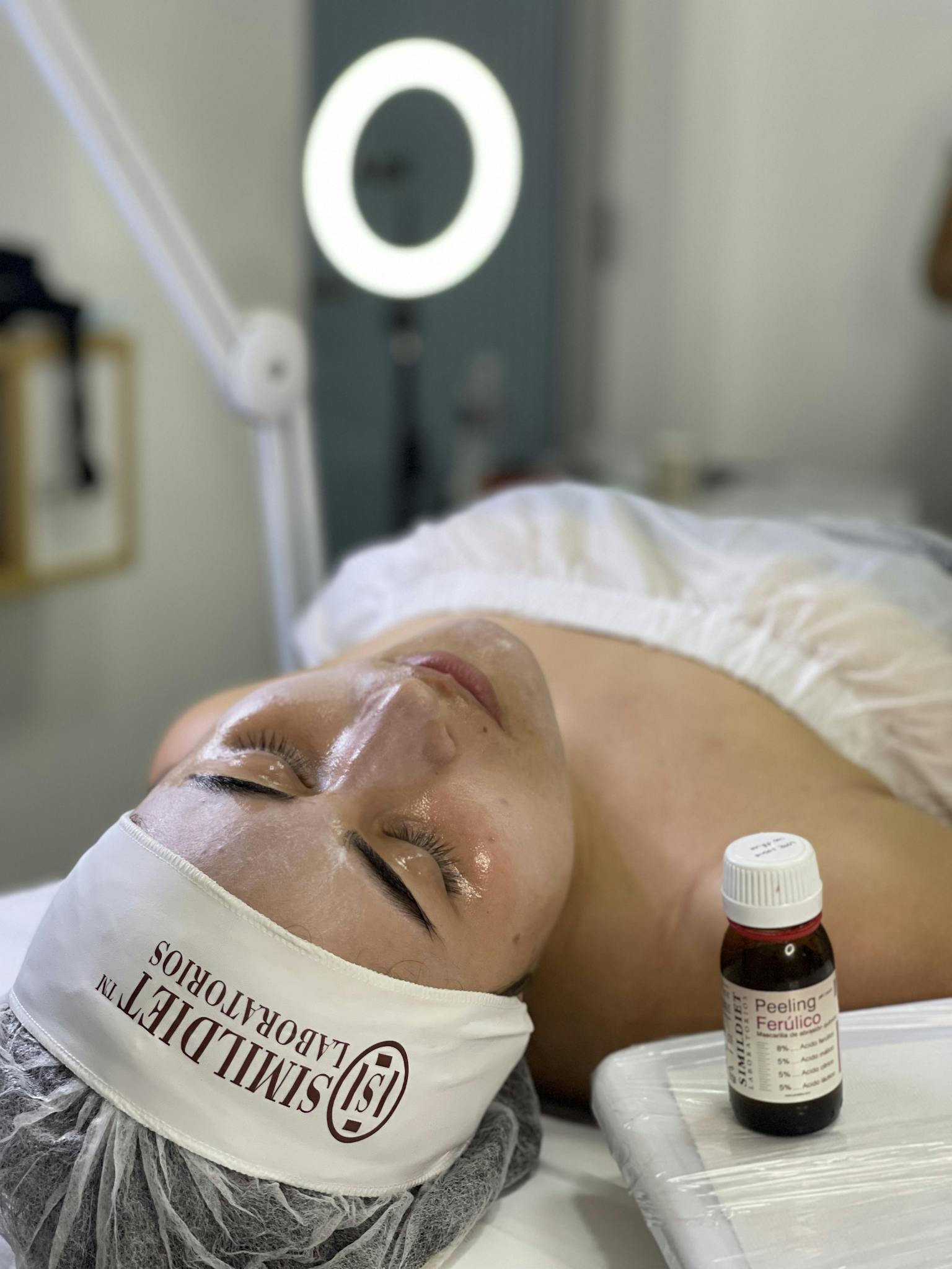 A woman relaxing during a facial peeling session featuring skincare products in a spa setting.