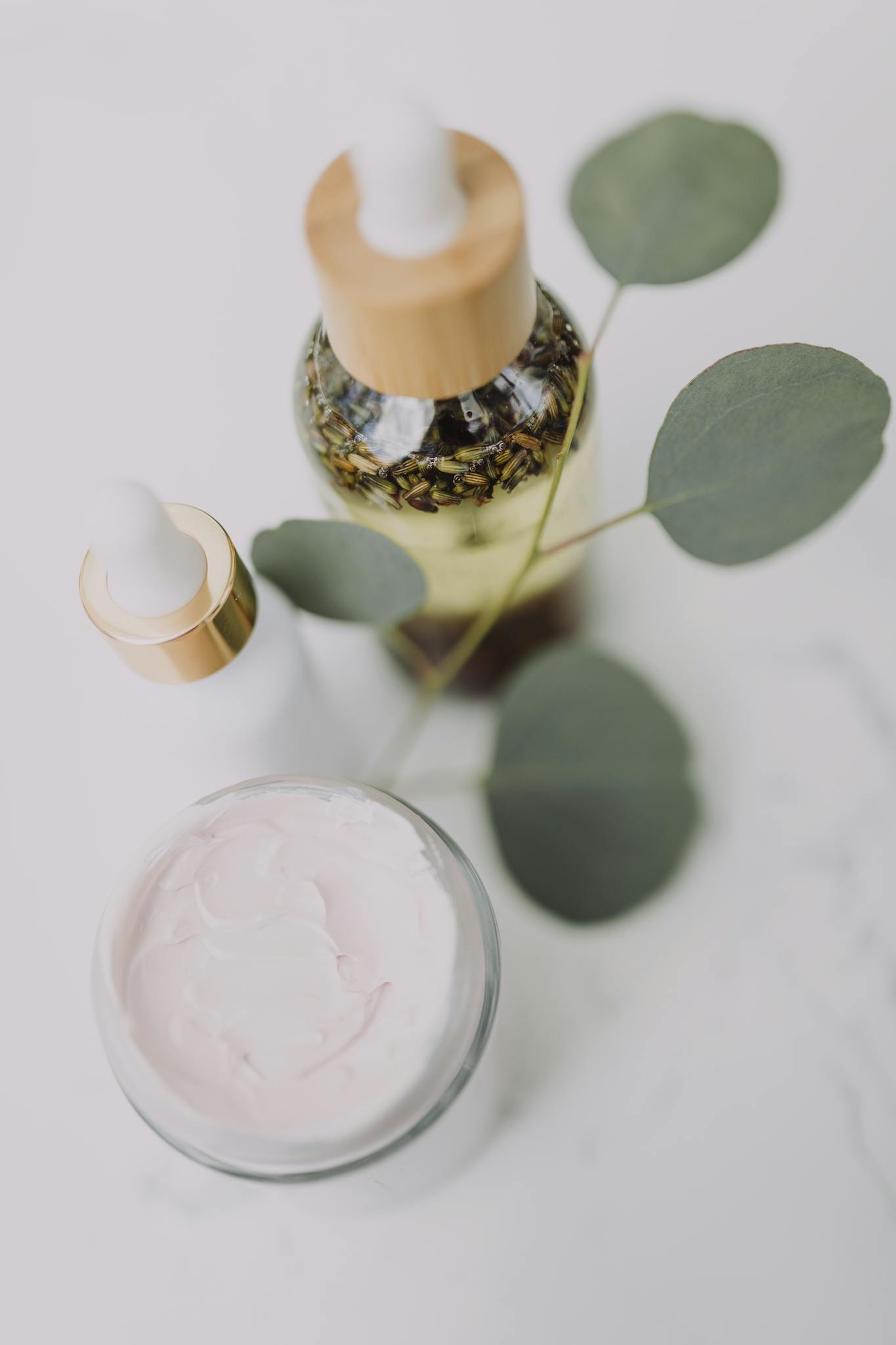 Minimalist skincare display featuring creams and oils with eucalyptus leaves.